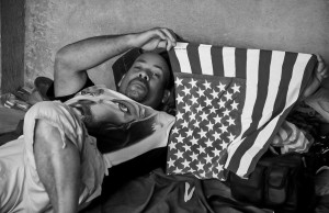 Adalberto sostiene una bandera estadounidense mientras descansa en un alojamiento para refugiados en La Cruz.