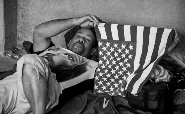 Adalberto sostiene una bandera estadounidense mientras descansa en un alojamiento para refugiados en La Cruz.