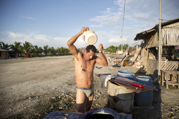 Un hombre se da un baño al lado de las ruinas de su casa, en el pueblo pesquero de La Chorrera. Los sobrevivientes del terremoto que han decidido quedarse en el lugar, junto con los voluntarios, han ideado mecanismos para abastecerse de lo necesario para sobrellevar la etapa de la reconstrucción.